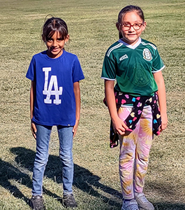 Two elementary school girls outside on the school field