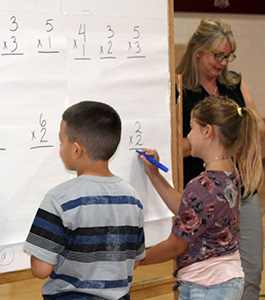 Students writing equations on large paper