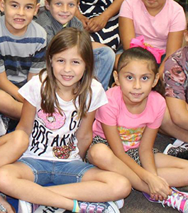 Smiling students pose together with their legs crossed